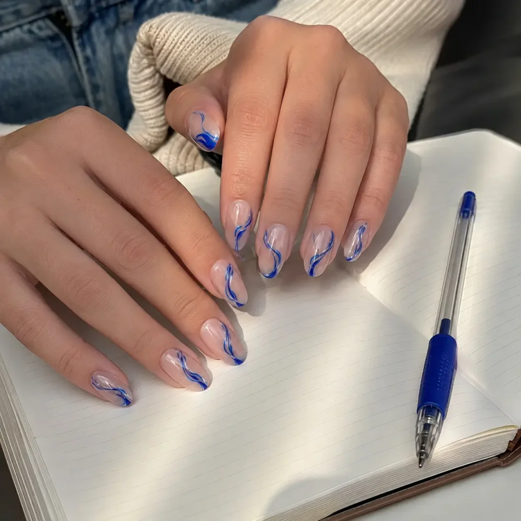 Back-to-school nail with abstract blue ink swirl nail art on a nude base