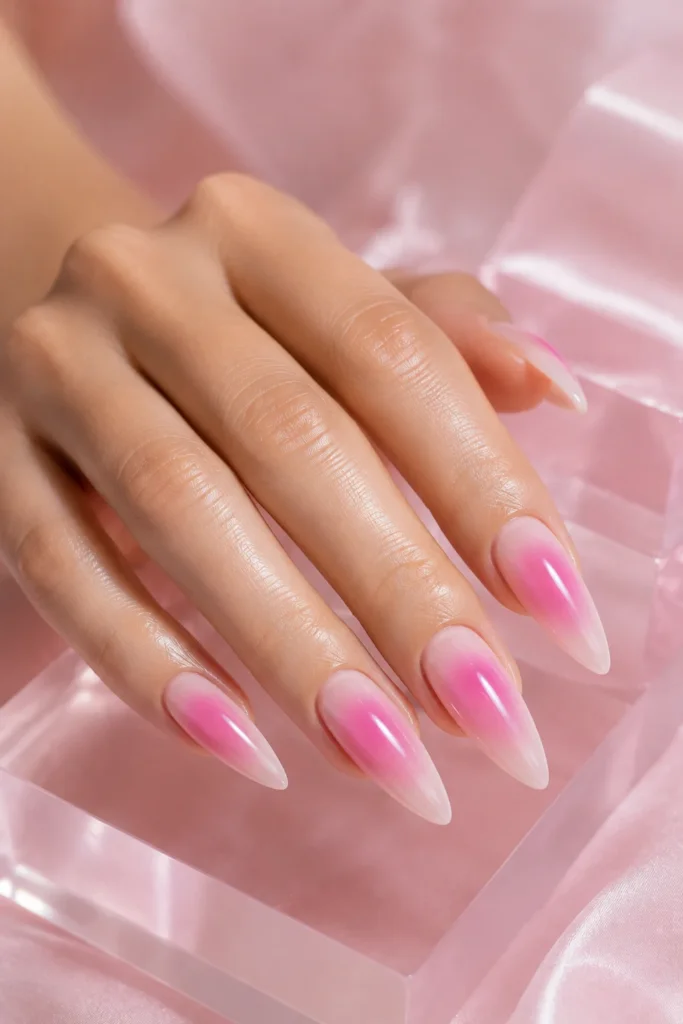Long stiletto nails with soft pink aura nail art and a glossy glass finish
