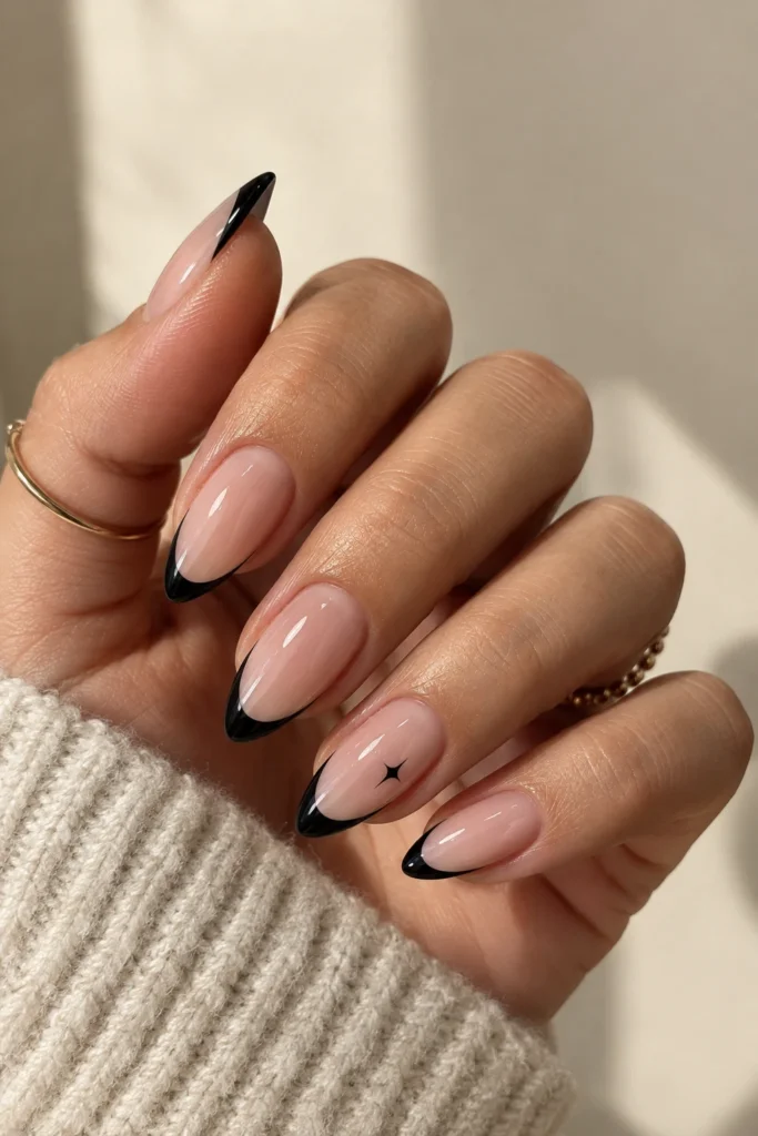 Almond nails with thin black French tips and a tiny star