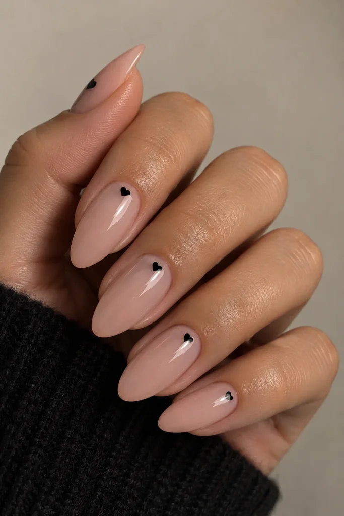 Sheer nude nails with tiny black heart accents